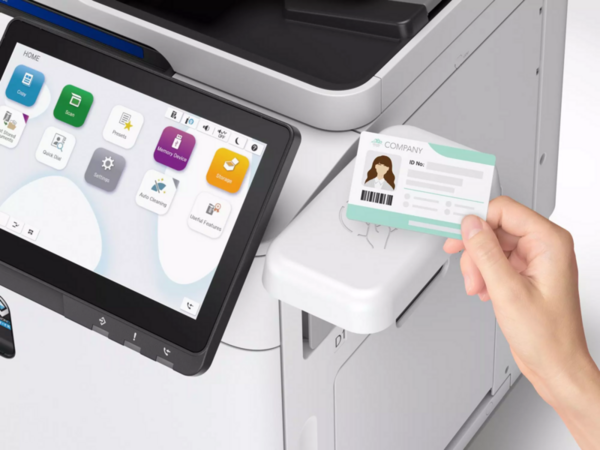 Ein Druckerausweis wird vor einem Druckerdisplay gehalten.